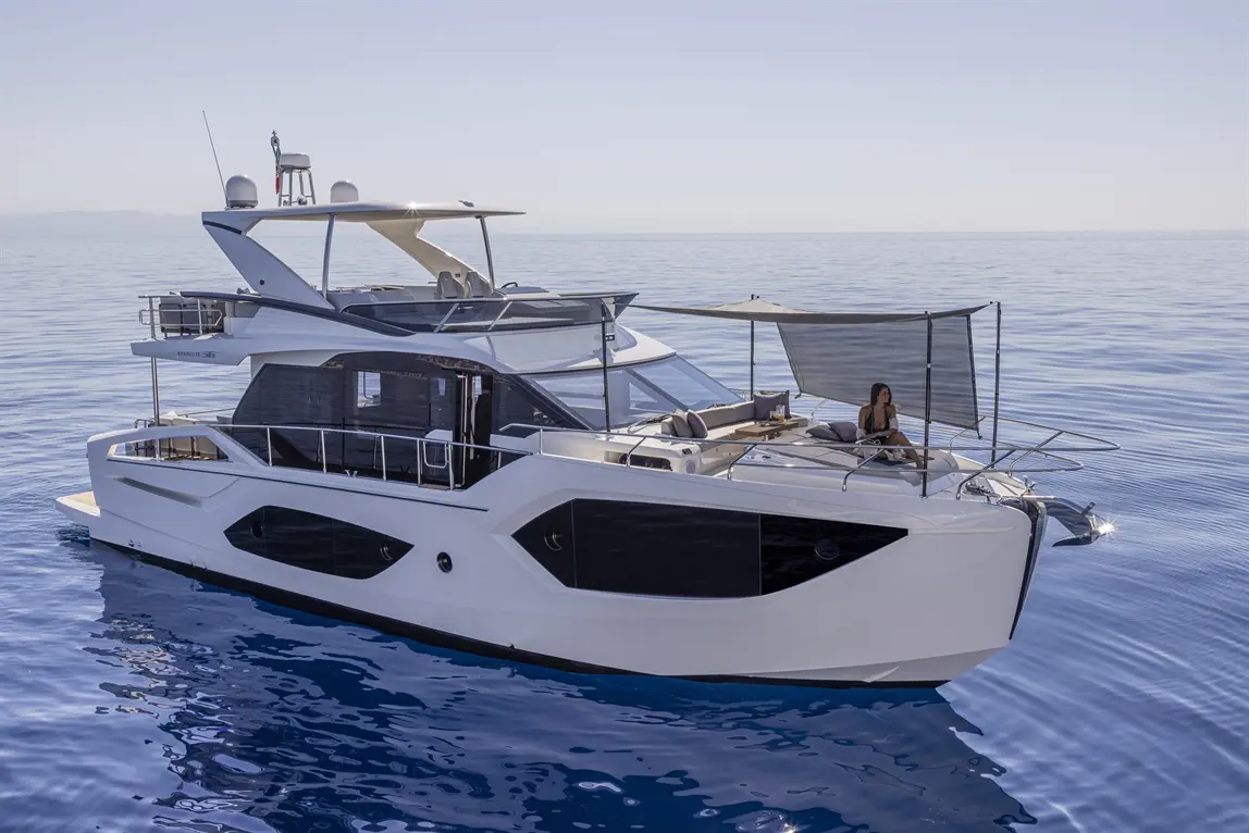 A luxury yacht on calm waters, featuring a woman relaxing under a sunshade on the deck, with a clear blue sky above.